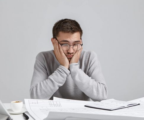 confused-male-architect-makes-fault-keeps-hand-on--5L392NR