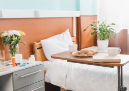cookies on plate, cups and book on table in hospital room