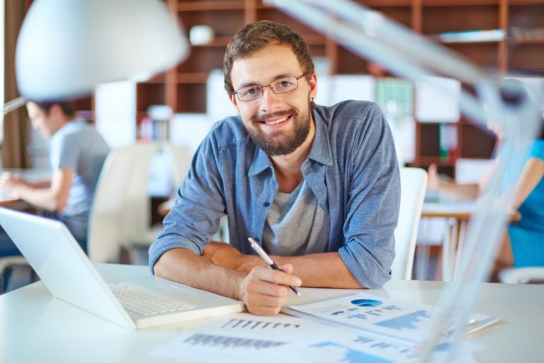 Handsome businessman in casual working in office on background of his partners